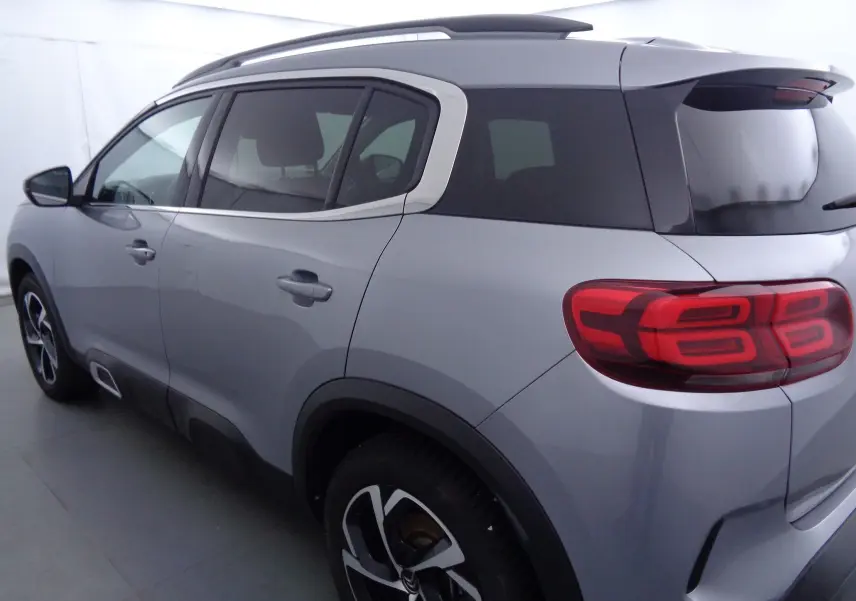 Vue 3/4 arrière droit d'un Citroën C5 Aircross gris Artense métallisé avec toit noir et feux arrière LED distinctifs.