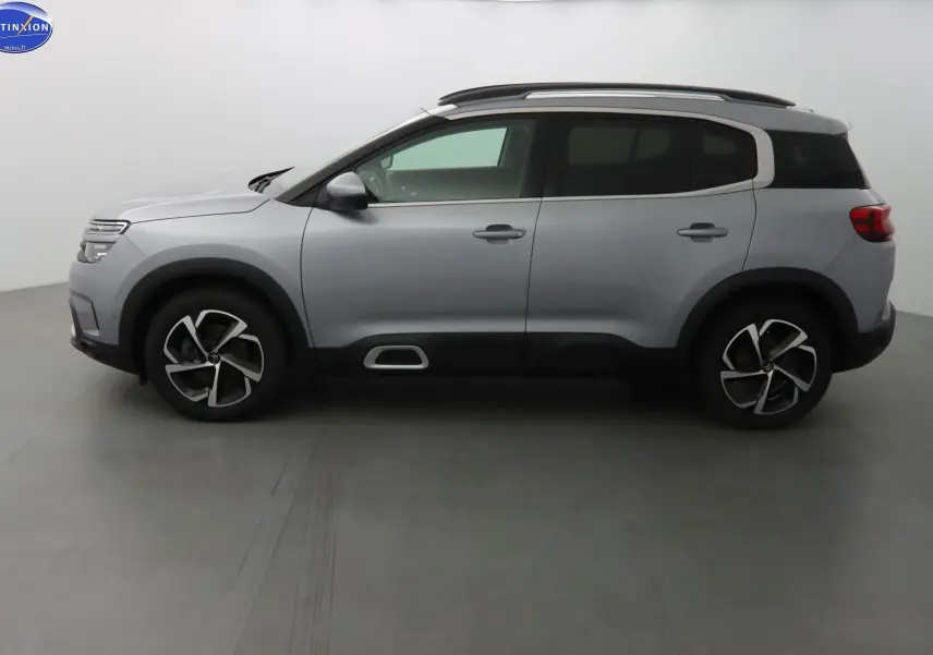 Profil côté gauche d'un Citroën C5 Aircross gris Artense métallisé avec jantes bi-ton et barres de toit.