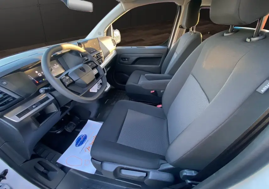 Vue intérieure côté conducteur du Peugeot Expert cabine approfondie 2025, sièges tissu bi-ton gris et noir.