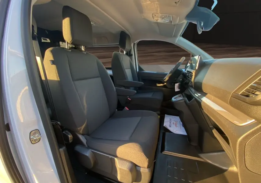 Vue intérieure côté conducteur du Peugeot Expert cabine approfondie blanc Icy, sièges tissu gris avec accoudoirs et tableau de bord moderne.