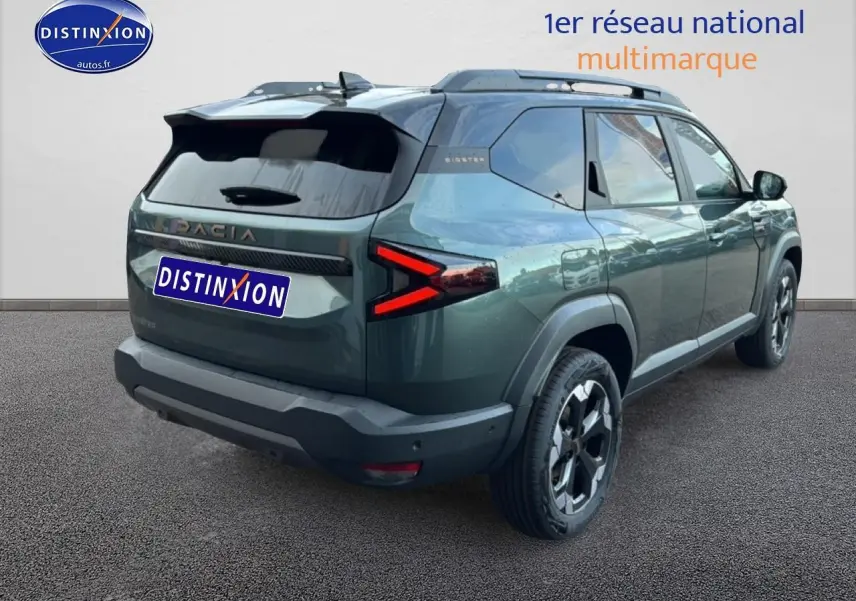 Vue 3/4 arrière droite du Dacia Bigster vert cèdre avec feux arrière LED en forme de flèche et barres de toit noires.