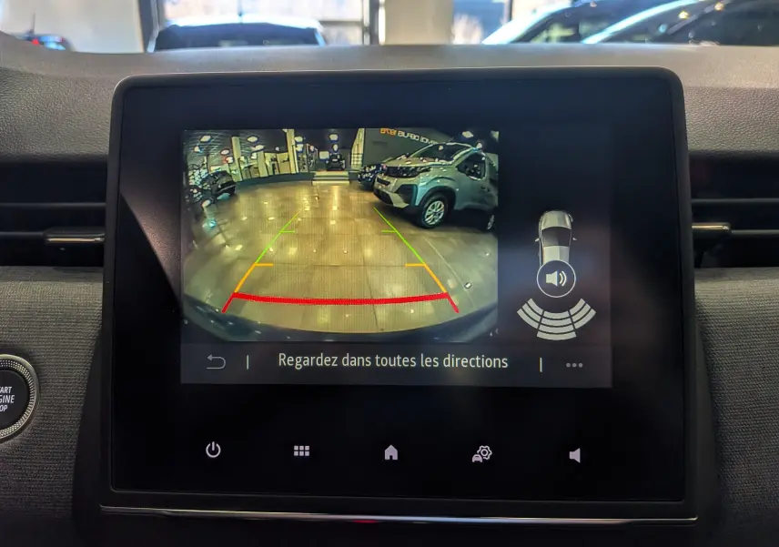 Écran multimédia montrant la caméra de recul avec vue arrière d’un véhicule blanc dans un garage lumineux.