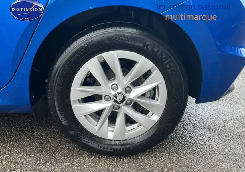 Gros plan sur la roue arrière droite d'une Skoda Fabia bleu 2025 avec jante alu et logo Skoda au centre.