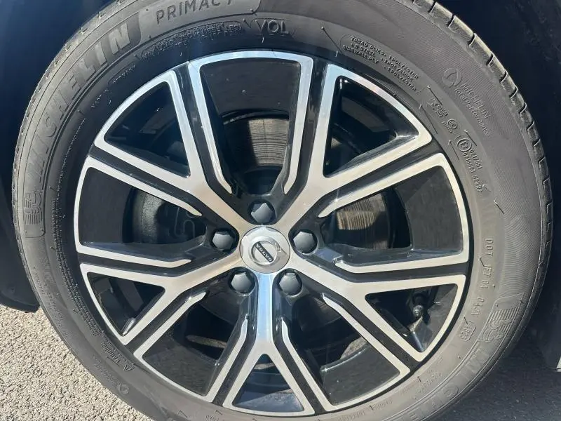 Gros plan sur la jante alliage noire et argentée d’une Volvo S60 2024, pneu Michelin visible sur sol asphalté.