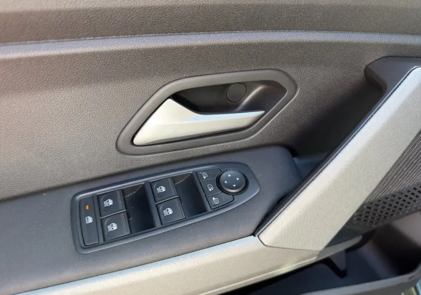 Gros plan sur la commande des vitres et poignée de porte intérieure côté conducteur d'une Dacia Bigster 2025 vert.