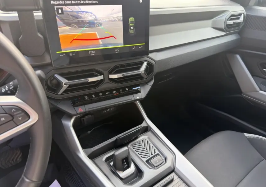 Vue intérieure du tableau de bord et console centrale du Dacia Bigster 2025, avec écran tactile et levier de boîte auto.