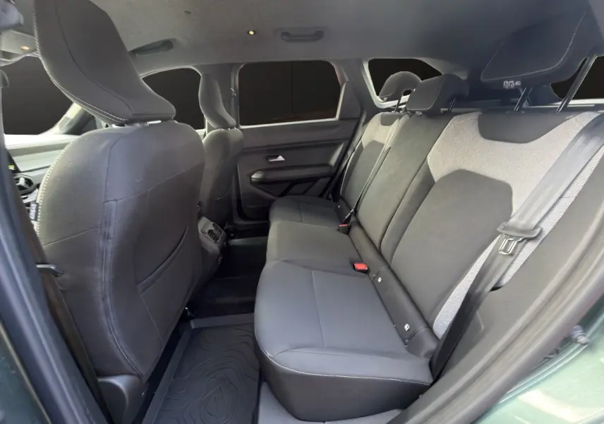 Vue intérieure côté gauche montrant la banquette arrière noire et grise du Dacia Bigster Journey Hybrid 2025 vert avec attelage.