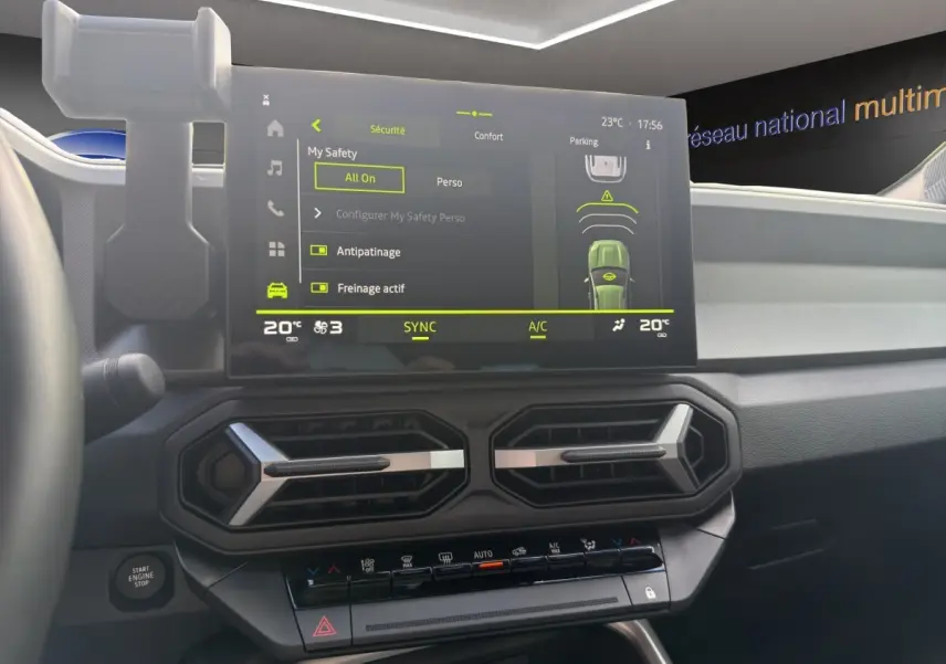 Vue intérieure du tableau de bord du Dacia Bigster vert, écran tactile multifonctions et commandes climatisation visibles.