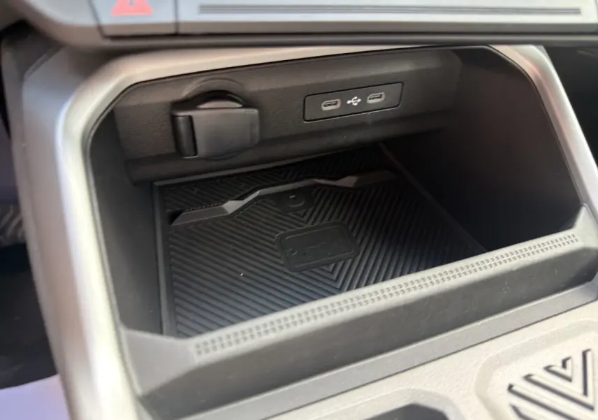 Gros plan sur la zone de recharge sans fil et ports USB dans l'habitacle noir du Dacia Bigster Journey hybride 2025.