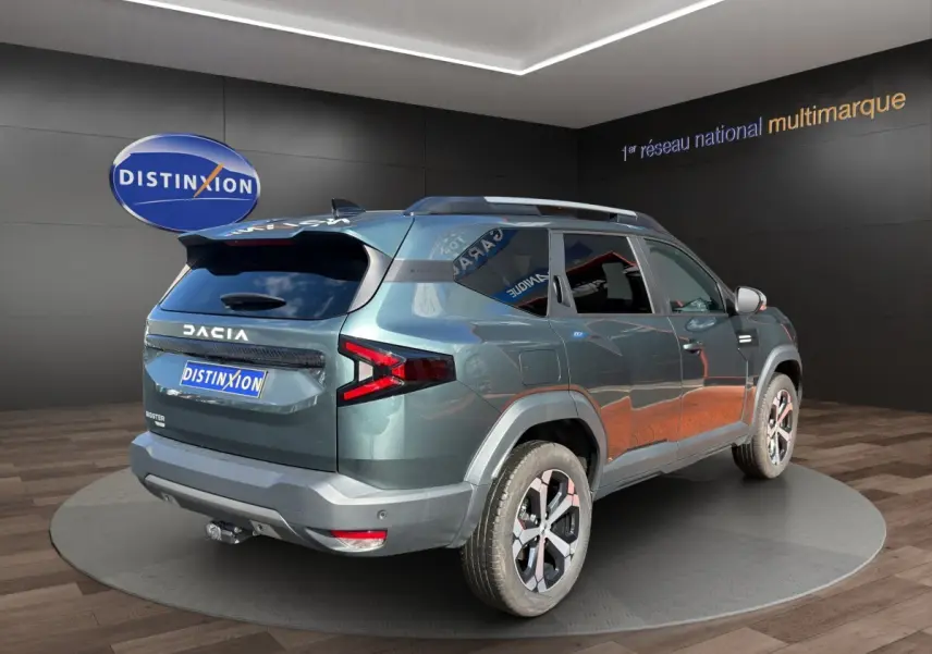 Vue 3/4 arrière droite du Dacia Bigster vert avec attelage RDSO et jantes alliage en showroom.