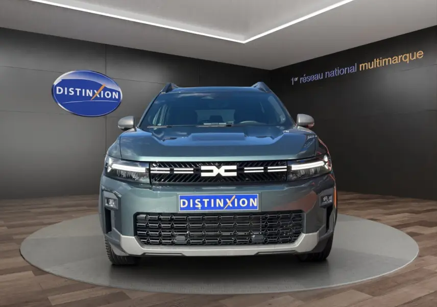 Vue avant du Dacia Bigster vert 2025 avec calandre noire et logo central distinctif, présenté en showroom.