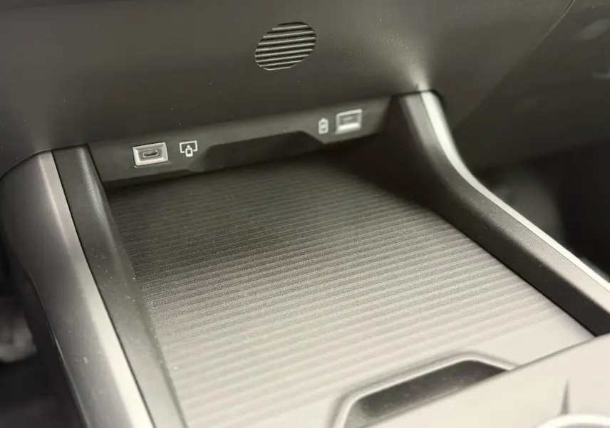 Gros plan sur la console centrale du Jeep Compass 2026, montrant le chargeur sans fil et ports USB.