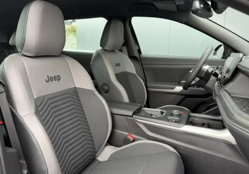 Vue intérieure côté conducteur du Jeep Compass 2026, sellerie mixte gris anthracite avec logo Jeep brodé sur les sièges.