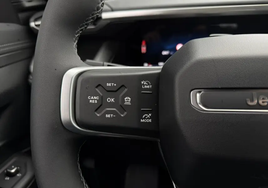 Gros plan sur le volant noir du Jeep Compass 2026 avec commandes intégrées et logo Jeep visible.