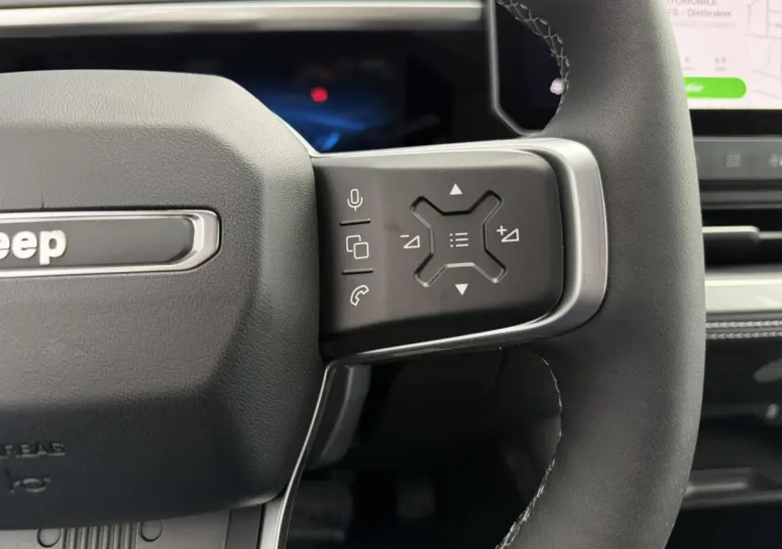 Gros plan sur la partie droite du volant noir du Jeep Compass 2026, avec commandes multifonctions et écran tactile visible.