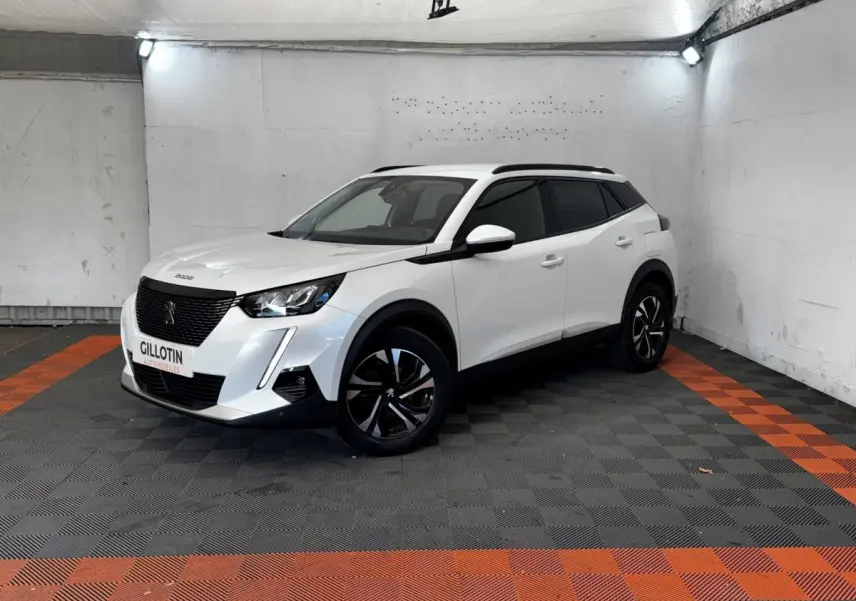 Peugeot 2008 blanc en 3/4 avant droit, avec jantes noires et toit noir dans un garage éclairé.