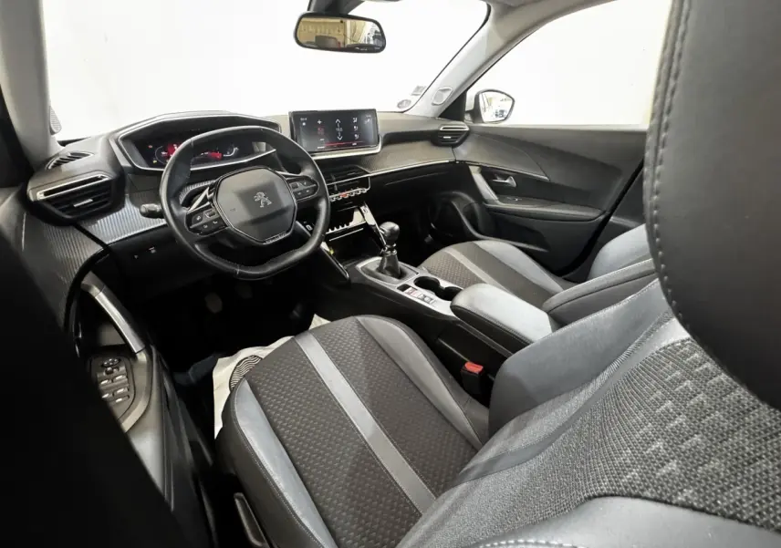 Intérieur de la Peugeot 2008 blanc, vue côté conducteur, volant cuir multifonctions et écran tactile central visible.