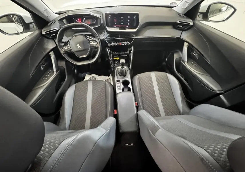 Vue intérieure avant du Peugeot 2008 blanc, montrant le volant cuir multifonctions et l’écran tactile central.