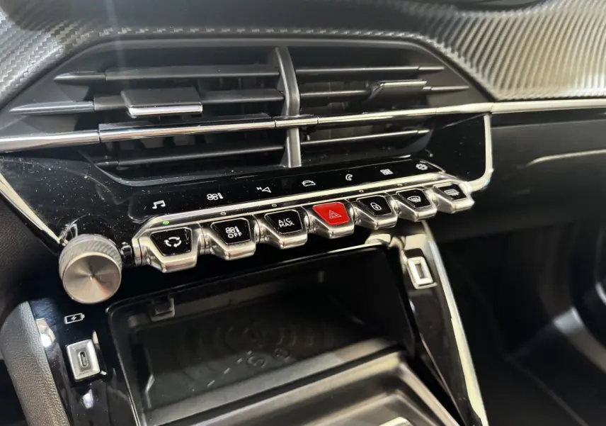 Vue rapprochée de la console centrale noire du Peugeot 2008 avec boutons chrome et écran tactile intégré.