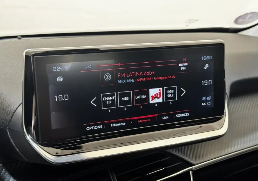 Écran tactile central de la Peugeot 2008 blanc, affichant la radio FM Latina avec interface moderne et bordure chromée.