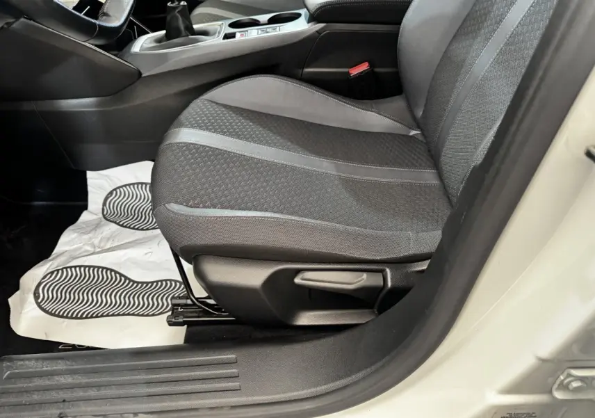 Vue rapprochée du siège avant droit gris foncé de la Peugeot 2008 blanche, avec levier de réglage manuel visible.