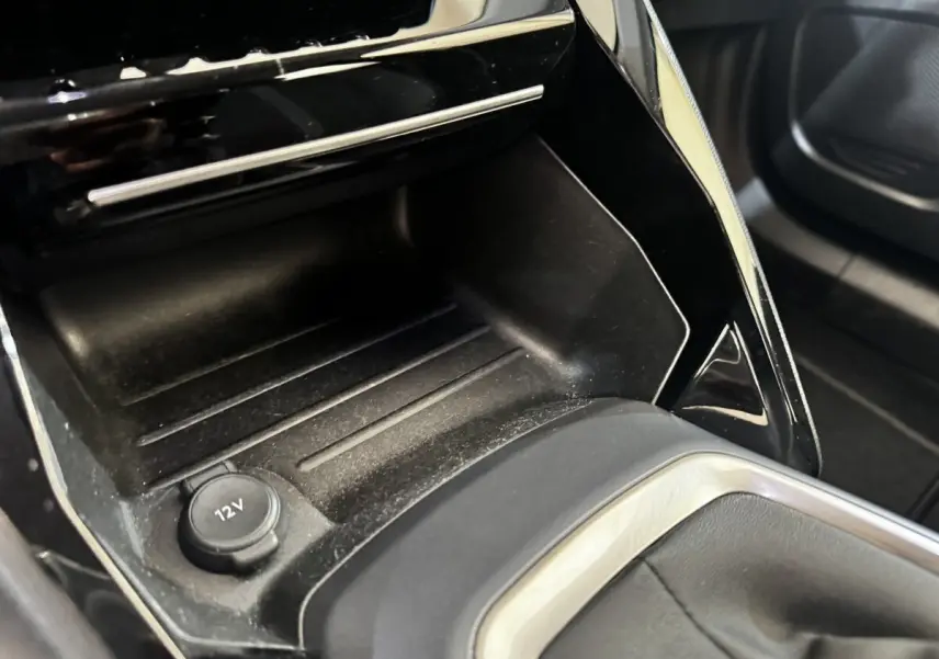 Gros plan intérieur sur la console centrale noire du Peugeot 2008 avec prise 12V visible et finitions argentées.