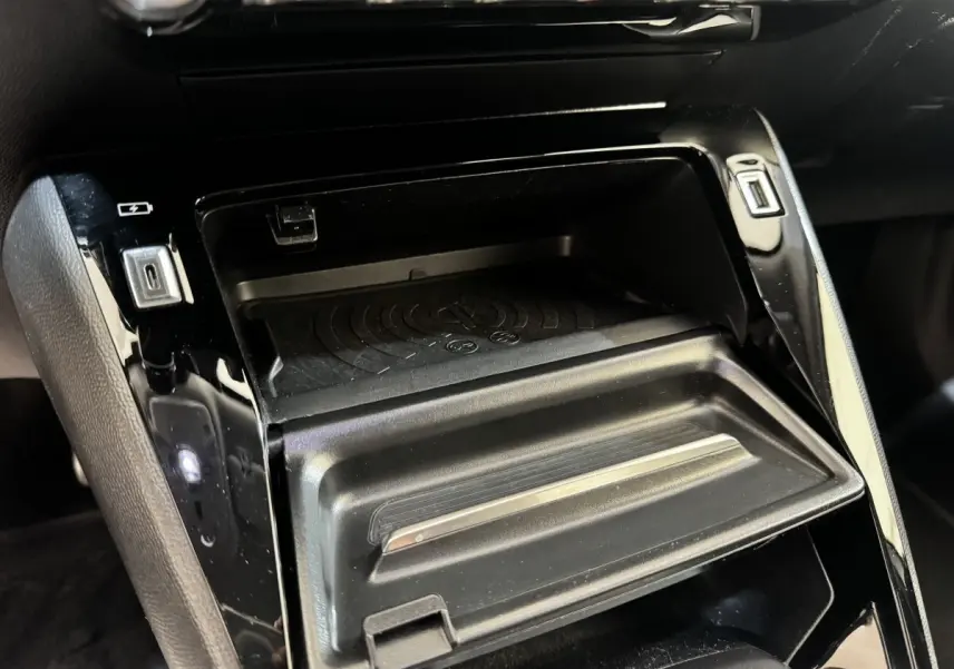 Gros plan intérieur sur la console centrale noire du Peugeot 2008, avec compartiment de rangement et ports USB visibles.