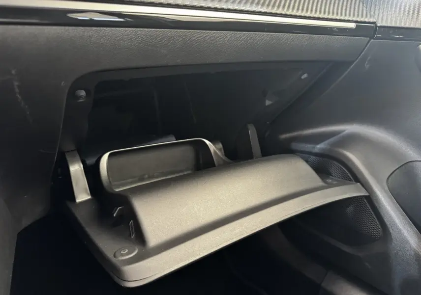 Gros plan sur la boîte à gants ouverte côté passager de l'intérieur noir du Peugeot 2008 blanc.
