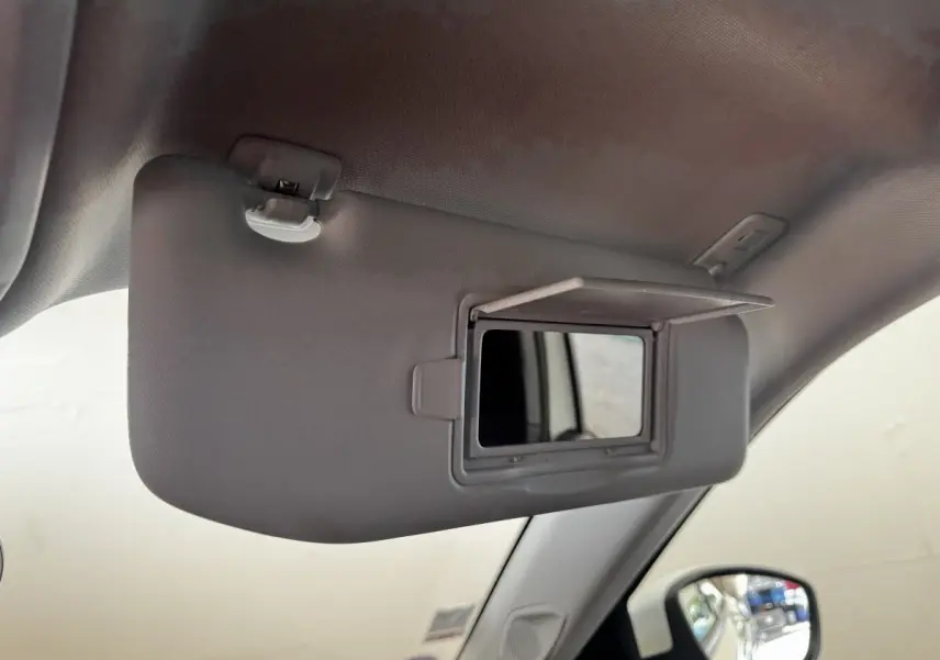 Détail du pare-soleil côté conducteur avec miroir de courtoisie ouvert dans l'habitacle blanc du Peugeot 2008.