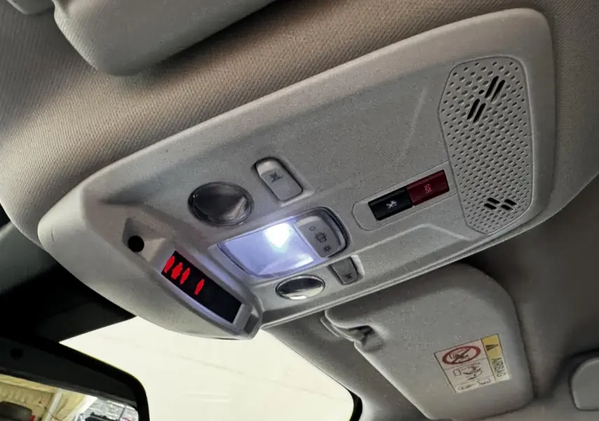 Plafonnier intérieur avec commandes lumineuses et bouton d'appel d'urgence dans un Peugeot 2008 blanc, vue en léger contre-plongée.