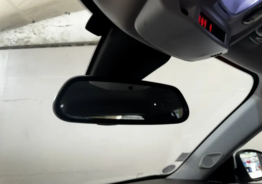 Rétroviseur intérieur noir du Peugeot 2008 blanc, vue depuis l'habitacle côté conducteur, avec pare-brise et rétroviseur extérieur visibles.