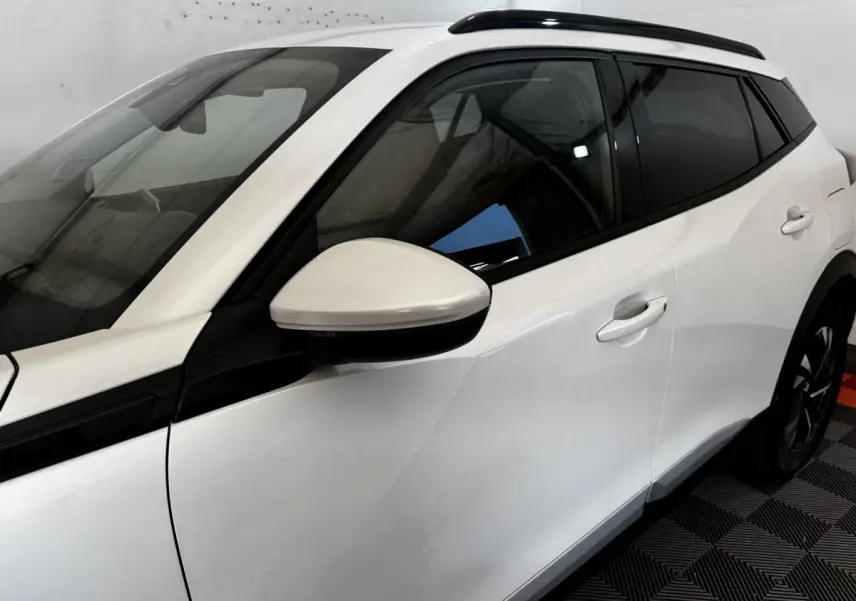 Vue de profil côté gauche du Peugeot 2008 blanc avec rétroviseur assorti et vitres teintées.