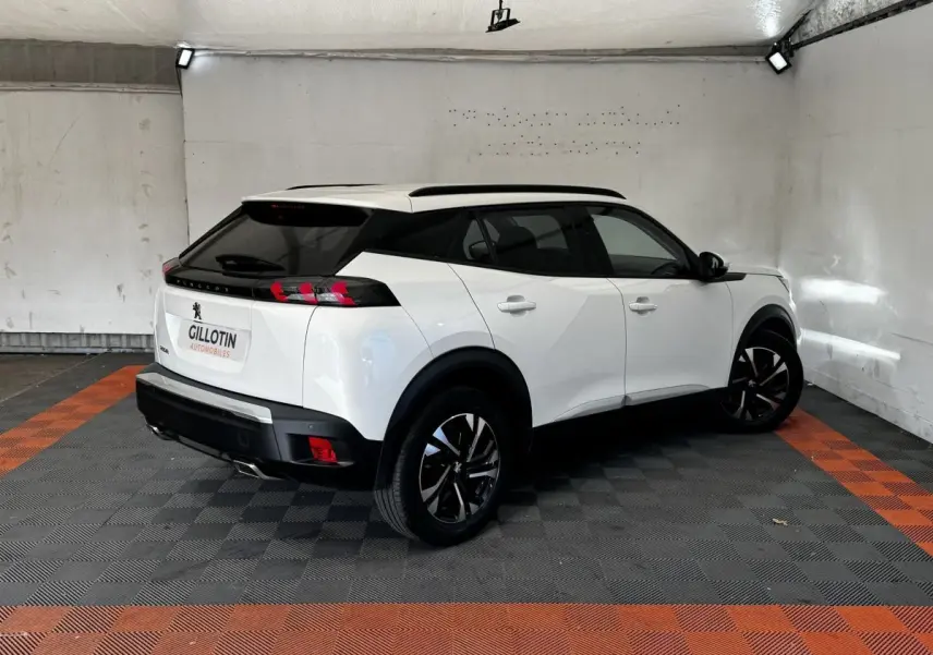 Peugeot 2008 blanc en 3/4 arrière droit, toit noir, feux arrière à LED et jantes alliage bicolores.