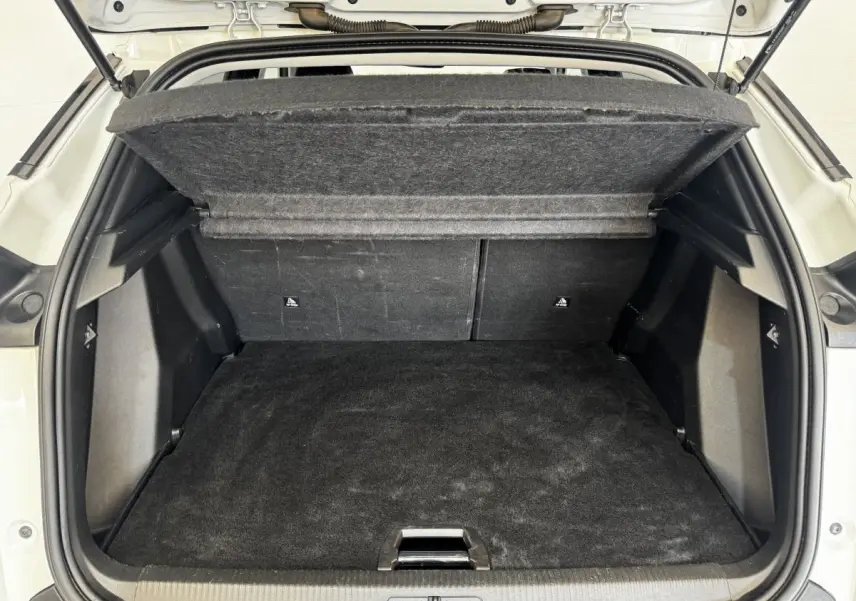 Coffre ouvert de Peugeot 2008 blanc, vue arrière montrant l'espace de chargement avec tablette de séparation relevée.