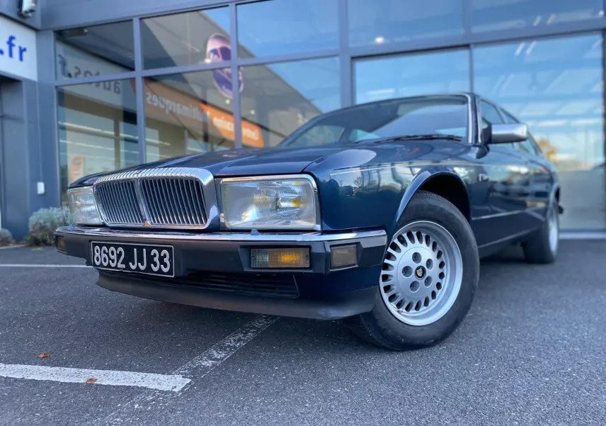 Jaguar XJ6 3.6 Sovereign bleu vue 3/4 avant mettant en valeur sa calandre chromée et ses jantes d'origine.