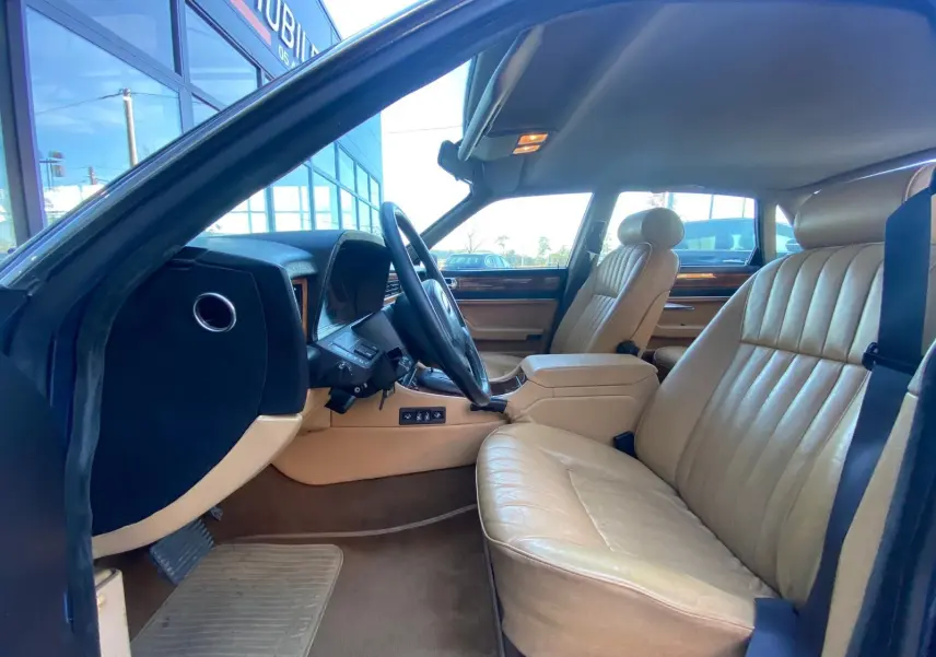 Intérieur beige de la Jaguar XJ6 3.6 Sovereign 1987, vue côté conducteur avec tableau de bord et sièges en cuir.