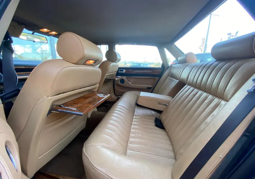 Vue intérieure arrière montrant les sièges en cuir beige et les plateaux en bois sur une Jaguar XJ6 3.6 Sovereign bleu de 1987.