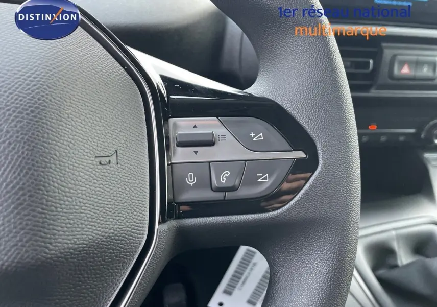 Gros plan sur les commandes du volant côté gauche du Peugeot Partner 2025, intérieur noir avec détails argentés.