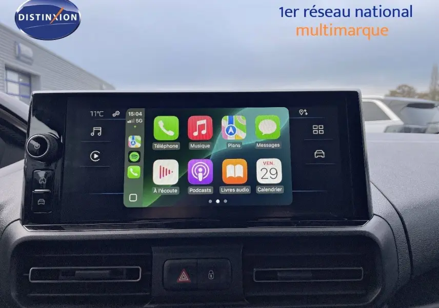 Écran tactile central du Peugeot Partner 2025, affichant les applications connectées, avec vue sur la planche de bord noire.