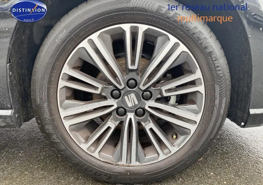 Gros plan sur la jante alliage gris foncé avec logo SEAT au centre, montée sur un pneu Goodyear.