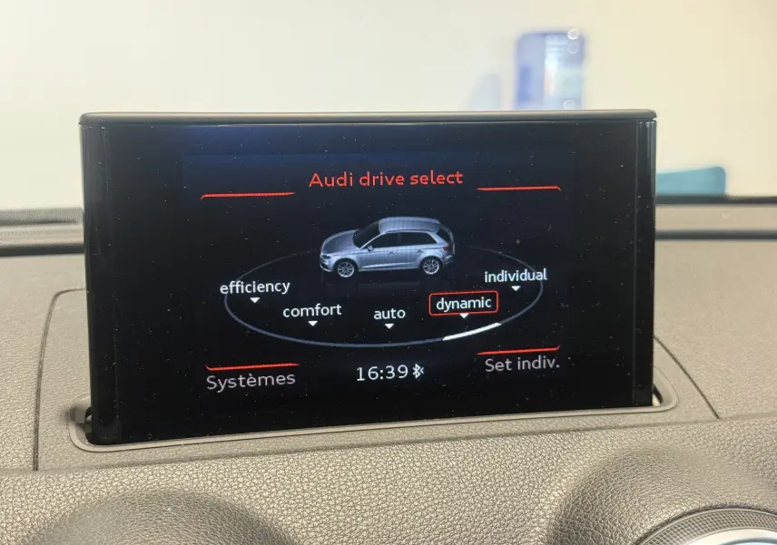 Écran central de l'Audi A3 Sportback blanc de 2015 montrant le mode de conduite dynamique sélectionné.