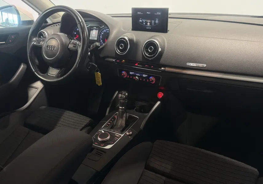 Intérieur noir d’Audi A3 Sportback 2015 vu côté conducteur, avec tableau de bord et console centrale équipée d’une boîte auto.