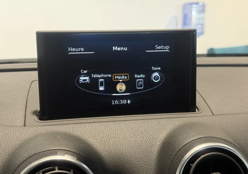 Écran central de l'Audi A3 Sportback 2015 affichant le menu multimédia, avec les aérateurs ronds en premier plan.