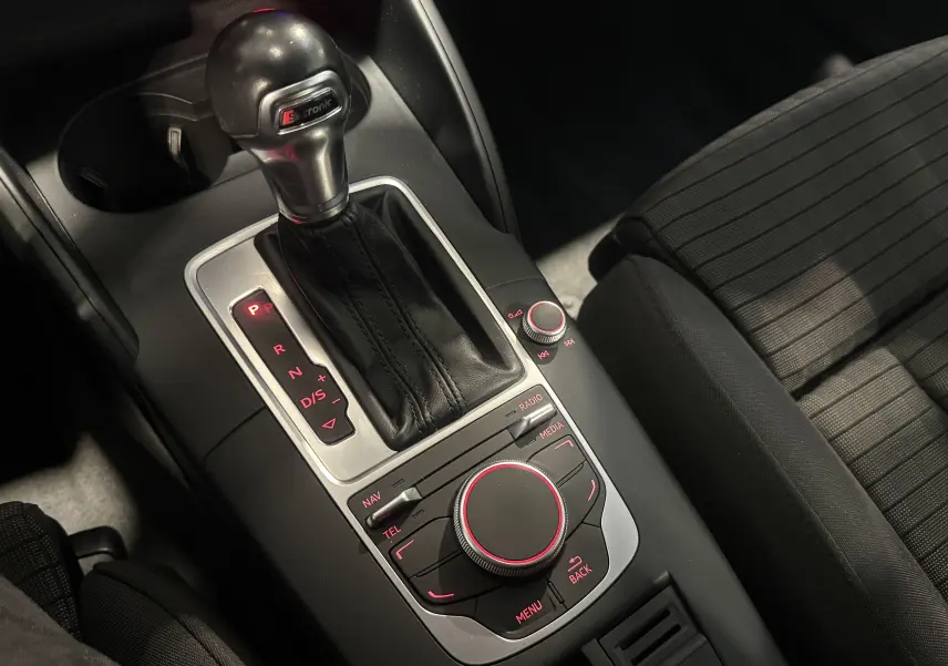 Vue rapprochée de la console centrale de l’Audi A3 Sportback 2015, avec levier de vitesses S-Tronic et commandes multimédia rétroéclairées.