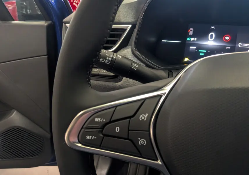 Détail du volant avec commandes intégrées et tableau de bord numérique, intérieur de Renault Clio V Bleu Iron, côté conducteur.