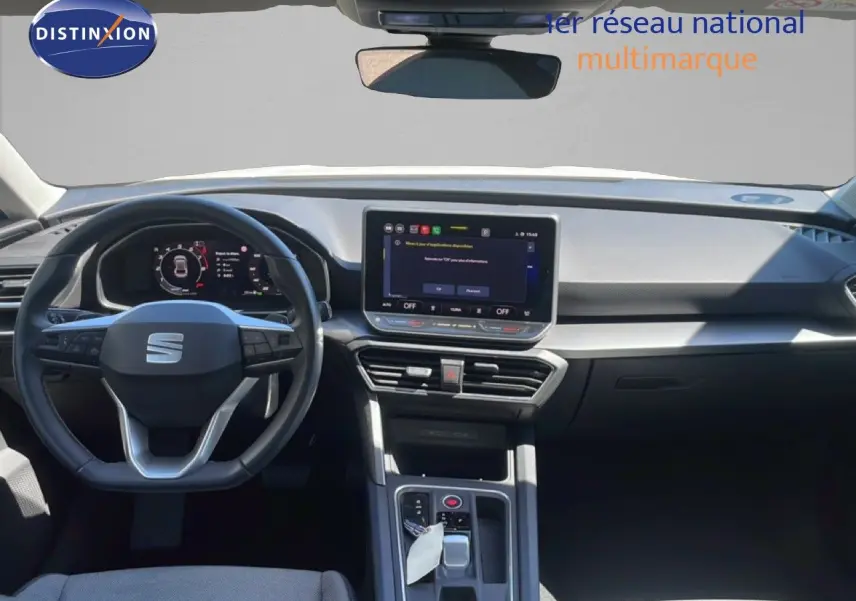 Vue intérieure avant du tableau de bord et volant noir du SEAT LEON blanc 2025 avec écran tactile central et boîte auto.