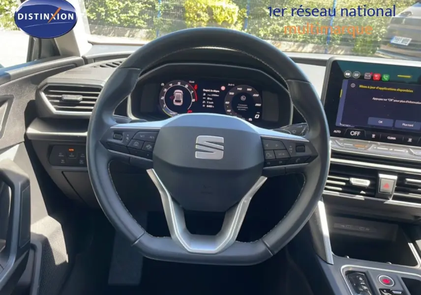 Vue intérieure centrée sur le volant multifonction d'une SEAT LEON 2025 avec tableau de bord numérique et écran tactile.