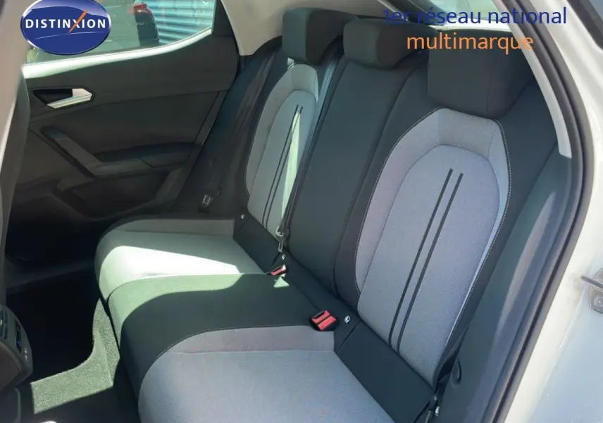 Vue intérieure sur les sièges arrière gris et noirs d’une SEAT LEON blanche, porte arrière droite ouverte.