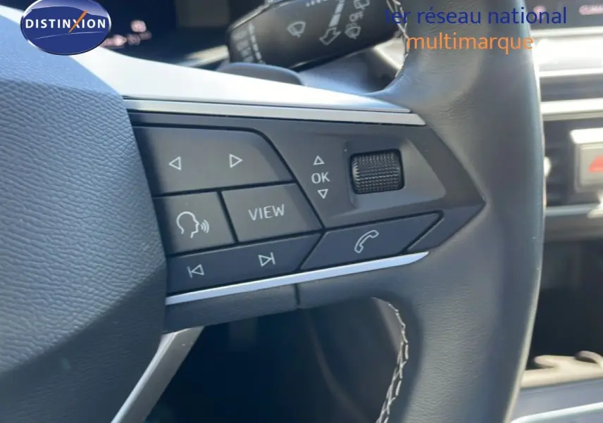 Gros plan sur les commandes au volant en cuir noir du SEAT Leon 1.5 TSI blanc, version 25e anniversaire.