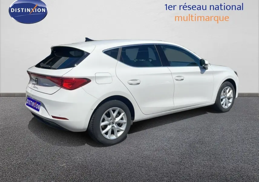 Vue 3/4 arrière droite d'une SEAT Leon blanche 2025 avec jantes alliage et vitres teintées.